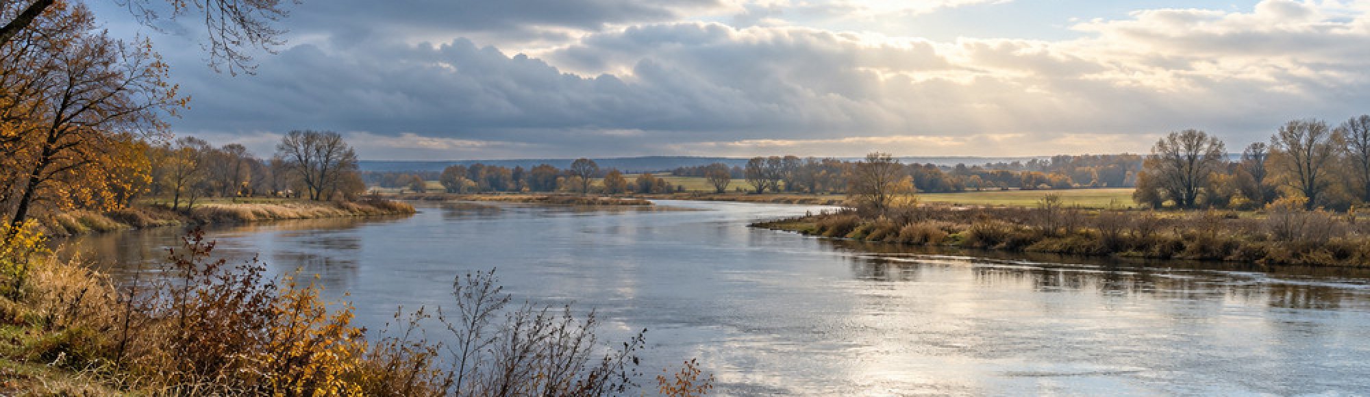 Herbstliche Flusslandschaft unter aufbrechenden Novemberwolken