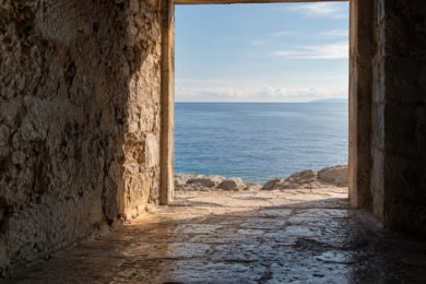 Blick aus einem schattigen Steindurchgang auf das offene Meer im Tageslicht