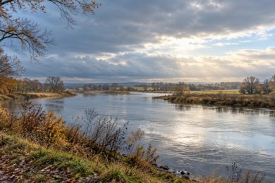 Herbstliche Flusslandschaft unter aufbrechenden Novemberwolken